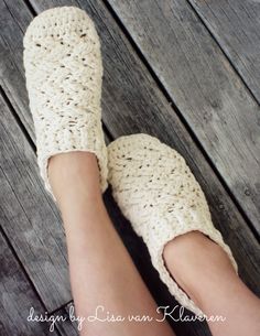 a woman's feet wearing crocheted slippers on top of a wooden floor