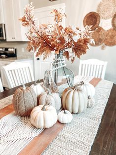 the table is set with white pumpkins and greenery