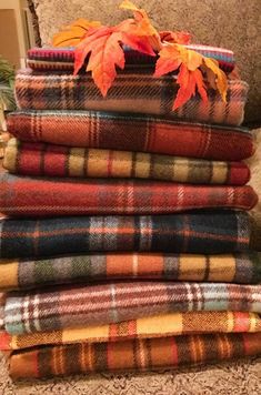 a pile of blankets sitting on top of a couch next to an orange and green leaf