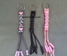 three key chains with hearts on them are shown in pink, black and grey colors