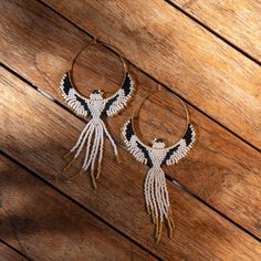 two hoop earrings with black and white designs on wooden floor next to wood planks