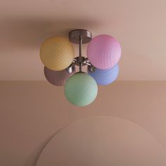 a multicolored light fixture hanging from the ceiling in a room with pink walls