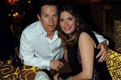 a man and woman sitting next to each other at a table with wine glasses on it