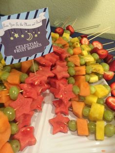 a platter filled with fruits and veggies next to a sign