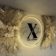 a sign that says the lodge on it with feathers around it and an x in the center