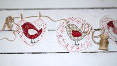 two red and white birds hanging from twine with hearts on the wall behind them