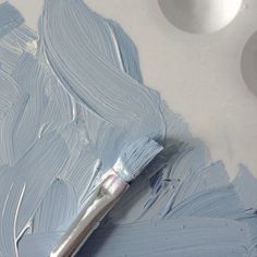 a paintbrush is sitting on top of a white surface with blue and gray colors