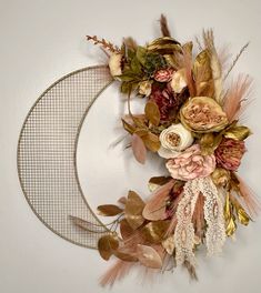 a wreath with dried flowers and leaves hanging on the wall next to a wire rack