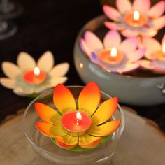 candles are floating in a bowl with flowers