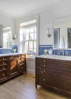 a large bathroom with two sinks and blue tile backsplashes on the walls