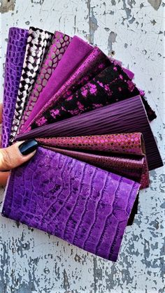 a person holding an assortment of purple and black fabrics