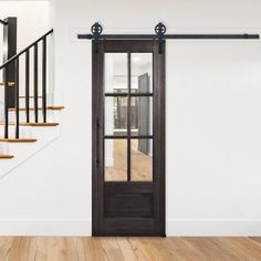 an empty room with wooden floors and white walls has a black door on the left