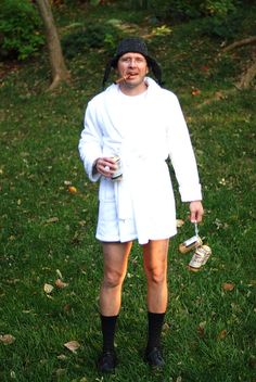 a man in a white robe is holding a cup and wearing black socks while standing on the grass