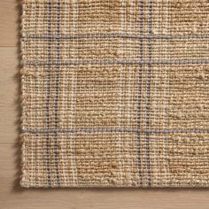 a close up of a rug on a wooden floor with a brown and blue checkered pattern