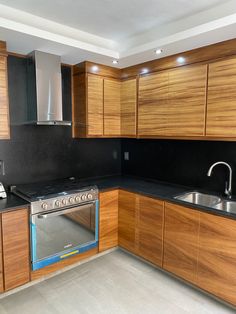 a kitchen with wooden cabinets and black counter tops, an oven in the middle is also stainless steel