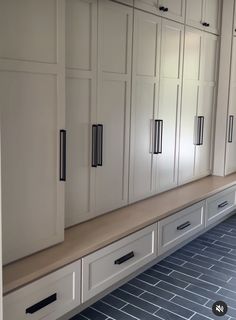 an empty kitchen with white cabinets and black tile flooring on the side walk way