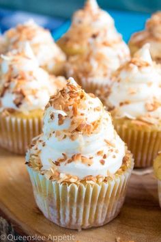 several cupcakes with white frosting and toasted coconut toppings on top