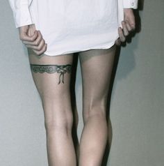 a person with tattoos on their legs standing in front of a white wall and wearing shorts