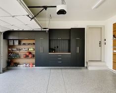 an empty garage with black cabinets and shelves