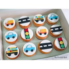 cupcakes decorated with cars and trucks are in a box