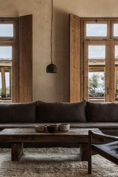 a living room filled with furniture and two large wooden windows next to eachother