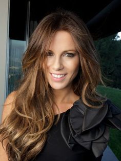 a black and white photo of a woman with long, wavy hair smiling at the camera