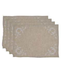 four napkins with white embroidered designs on them