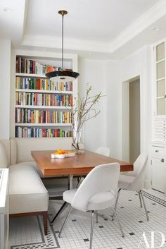 a dining room table and chairs with bookshelves in the backgroung