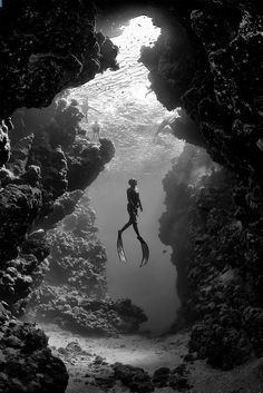 a person swimming in the water through a cave