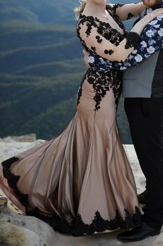 a man and woman standing next to each other on top of a mountain with mountains in the background