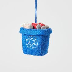 a blue felt ornament hanging from a string with two stuffed animals in it