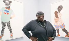 a woman standing in front of two paintings on the wall with her hands on her hips