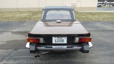 an old car parked in a parking lot with the license plate on it's back