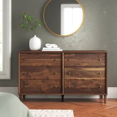 a wooden dresser sitting in front of a mirror on top of a hard wood floor