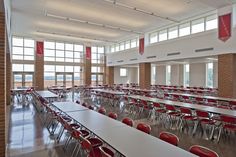 an empty classroom with red chairs and tables