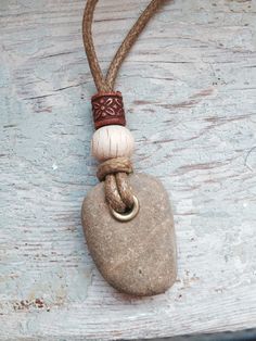 a rock with a ring on it is hanging from a rope that has been placed on a wooden surface