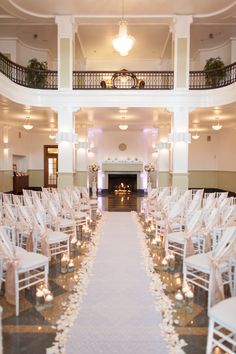 the aisle is lined with white chairs and candles