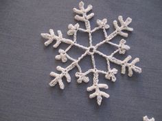 a snowflake made out of crochet on top of a gray surface