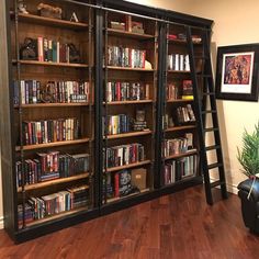 a ladder leaning up against a book case filled with lots of books on top of a hard wood floor