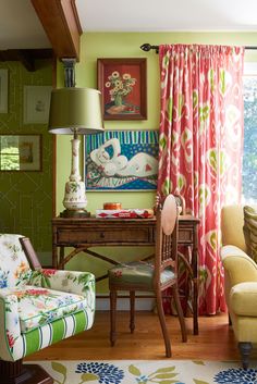 a living room filled with furniture and a painting hanging on the wall above a desk