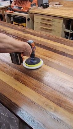 a person using a sander on top of a wooden table in a room with other furniture