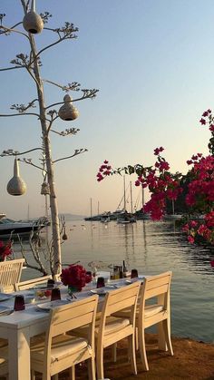 the table is set with white plates and place settings for dinner on the water's edge