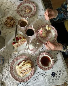 a table topped with plates filled with cake and cups of coffee next to each other