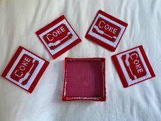 four red and white coasters sitting on top of a bed next to each other