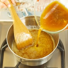 a person pouring sauce into a pan on top of a stove with a wooden spoon