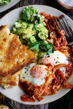 an egg, toast and vegetables on a white plate with a fork next to it