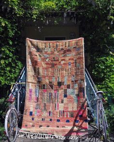 a bicycle parked in front of a building with a quilt on it's back