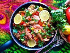 a bowl filled with food next to two tomatoes and lemons