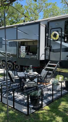 an rv is parked in the grass near a table and chairs