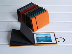 an assortment of colored folders sitting on top of a white wooden table next to a black binder